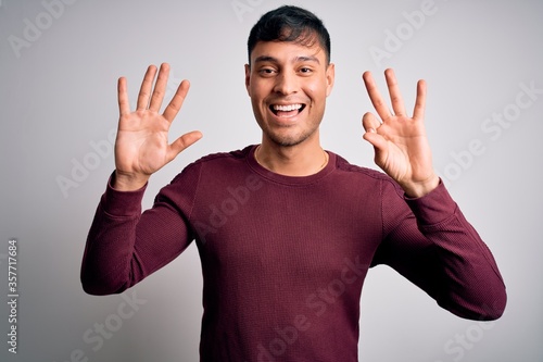 Young handsome hispanic man wearing casual shirt standing over white isolated background showing and pointing up with fingers number eight while smiling confident and happy.