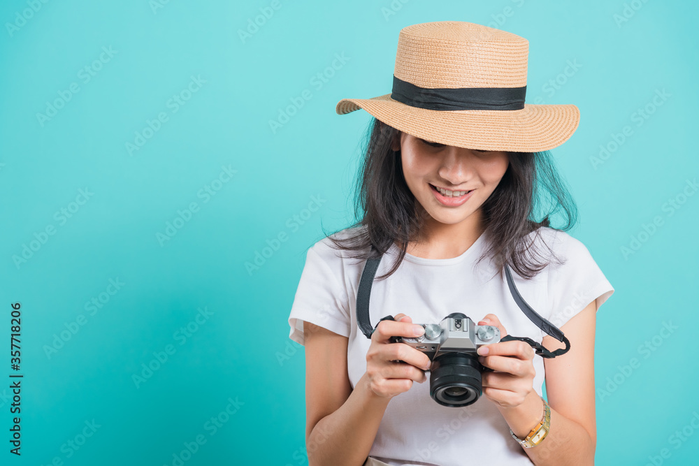 Traveler tourist happy Asian beautiful young woman smile in summer hat standing with mirrorless photo camera, shoot photo in studio on blue background with copy space for text Traveler tourist happy Asian beautiful young woman smile in summer hat standing with mirrorless photo camera, shoot photo in studio on blue background with copy space for text