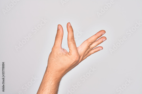 Hand of caucasian young man showing fingers over isolated white background picking and taking invisible thing, holding object with fingers showing space © Krakenimages.com