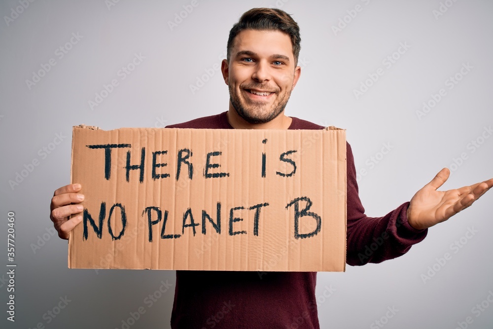 Young activist man holding protest banner for climate change and environment change very happy and excited, winner expression celebrating victory screaming with big smile and raised hands Young activist man holding protest banner for climate change and environment change very happy and excited, winner expression celebrating victory screaming with big smile and raised hands