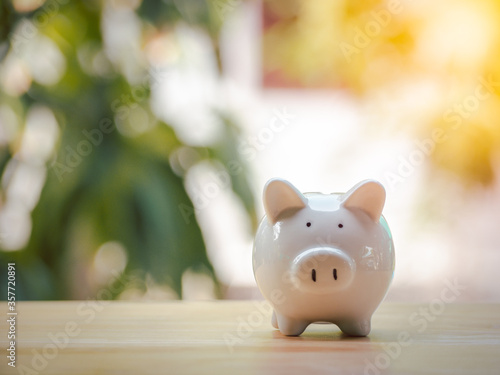 White piggy bank placed on a wooden table to save the money invest for the future. Concept for loan, property ladder, financial, mortgage, real estate investment, taxes and bonus.