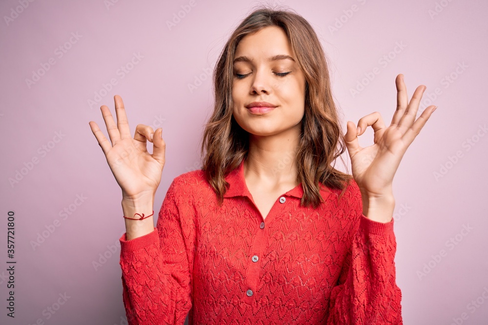 Young beautiful blonde casual girl over pink isolated background relax and smiling with eyes closed doing meditation gesture with fingers. Yoga concept. Young beautiful blonde casual girl over pink isolated background relax and smiling with eyes closed doing meditation gesture with fingers. Yoga concept.