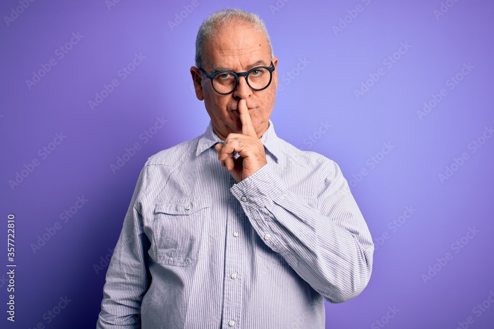 Middle age handsome hoary man wearing striped shirt and glasses over purple background asking to be quiet with finger on lips. Silence and secret concept. Middle age handsome hoary man wearing striped shirt and glasses over purple background asking to be quiet with finger on lips. Silence and secret concept.