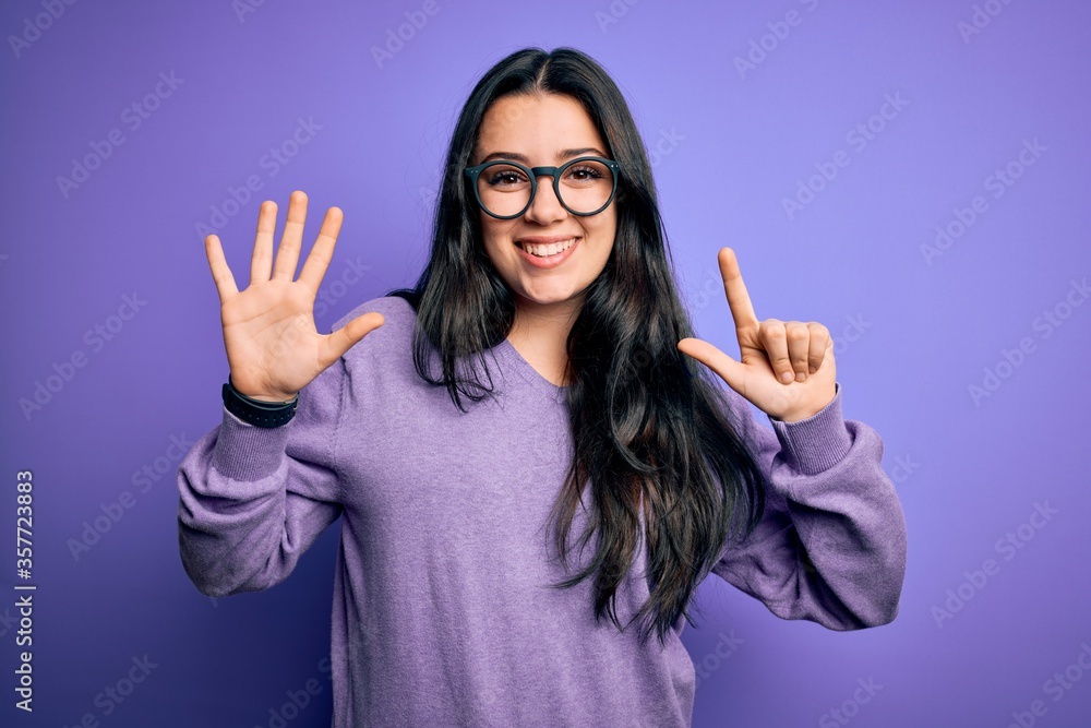 Young brunette woman wearing glasses over purple isolated background showing and pointing up with fingers number seven while smiling confident and happy. Young brunette woman wearing glasses over purple isolated background showing and pointing up with fingers number seven while smiling confident and happy.