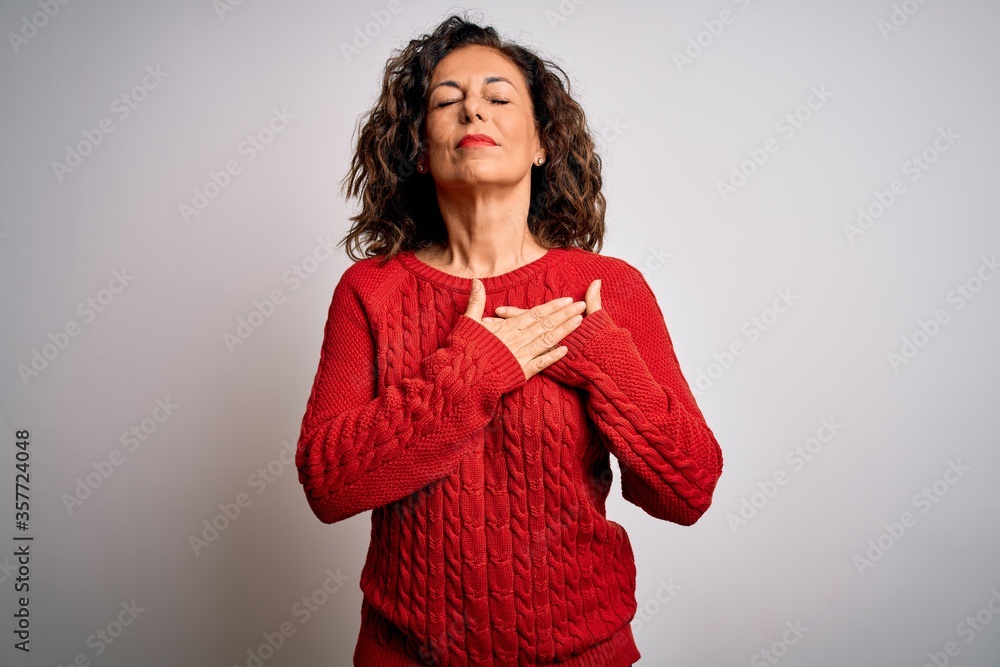 Middle age brunette woman wearing casual sweater standing over isolated white background smiling with hands on chest with closed eyes and grateful gesture on face. Health concept. Middle age brunette woman wearing casual sweater standing over isolated white background smiling with hands on chest with closed eyes and grateful gesture on face. Health concept.