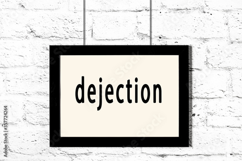 Photography Black frame hanging on white brick wall with inscription dejection