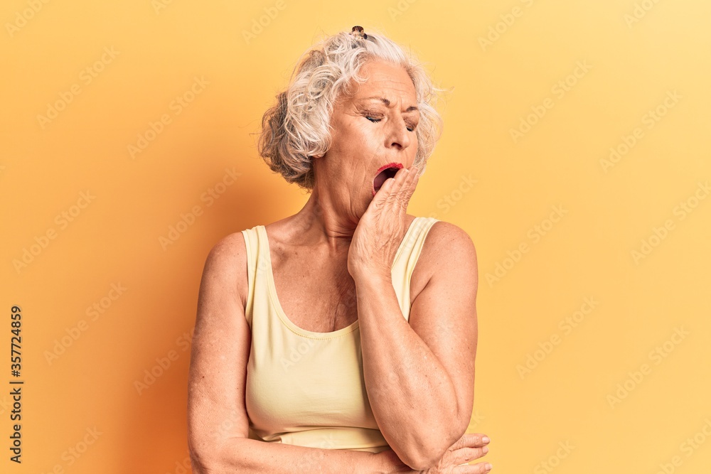 Senior grey-haired woman wearing casual clothes bored yawning tired covering mouth with hand. restless and sleepiness. Senior grey-haired woman wearing casual clothes bored yawning tired covering mouth with hand. restless and sleepiness.
