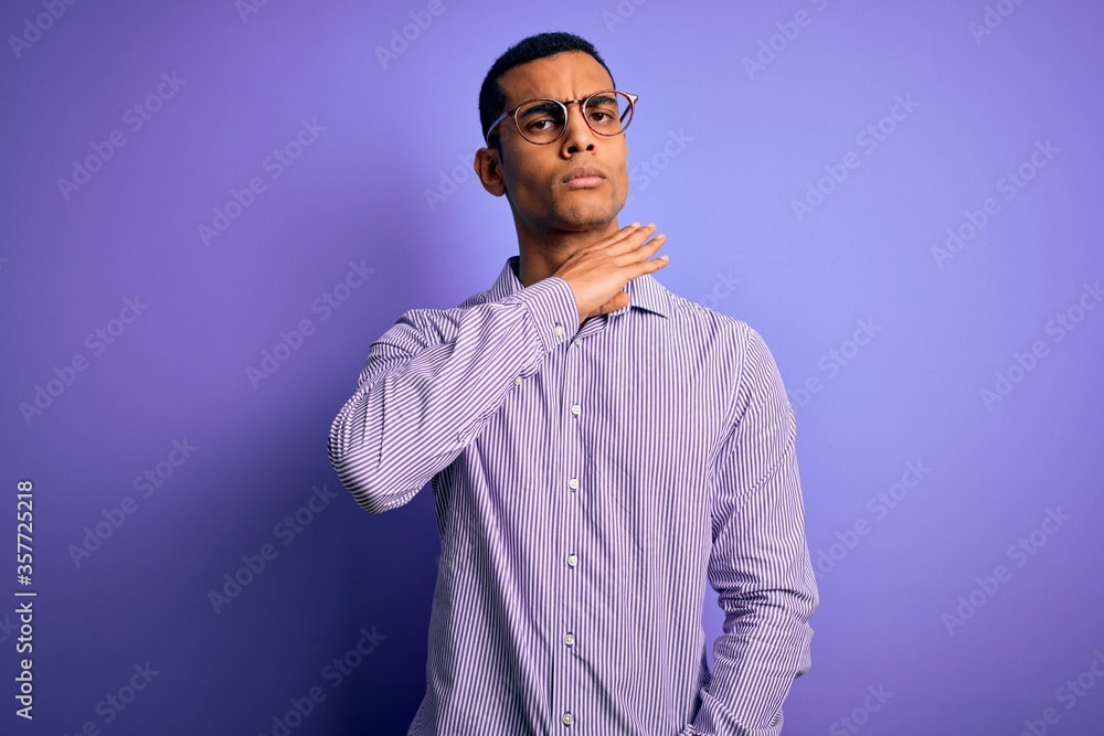 Handsome african american man wearing striped shirt and glasses over purple background cutting throat with hand as knife, threaten aggression with furious violence Handsome african american man wearing striped shirt and glasses over purple background cutting throat with hand as knife, threaten aggression with furious violence
