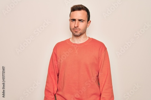 Young handsome man with blue eyes wearing casual sweater standing over white background skeptic and nervous, frowning upset because of problem. Negative person.