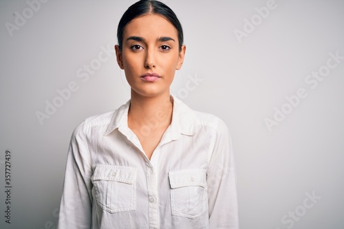 Obraz na plátně Young beautiful brunette woman wearing casual shirt over isolated white background with serious expression on face