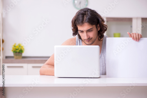 Young man holding blank paper at home