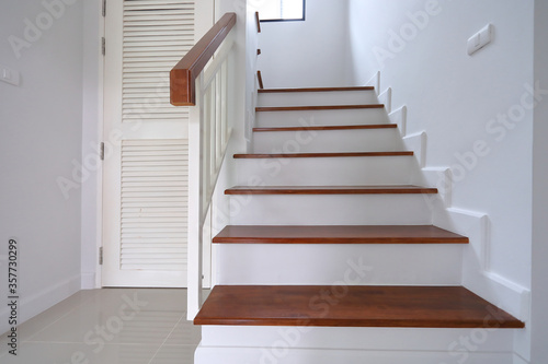 Fotografija brown wooden stair and white wall in residential house