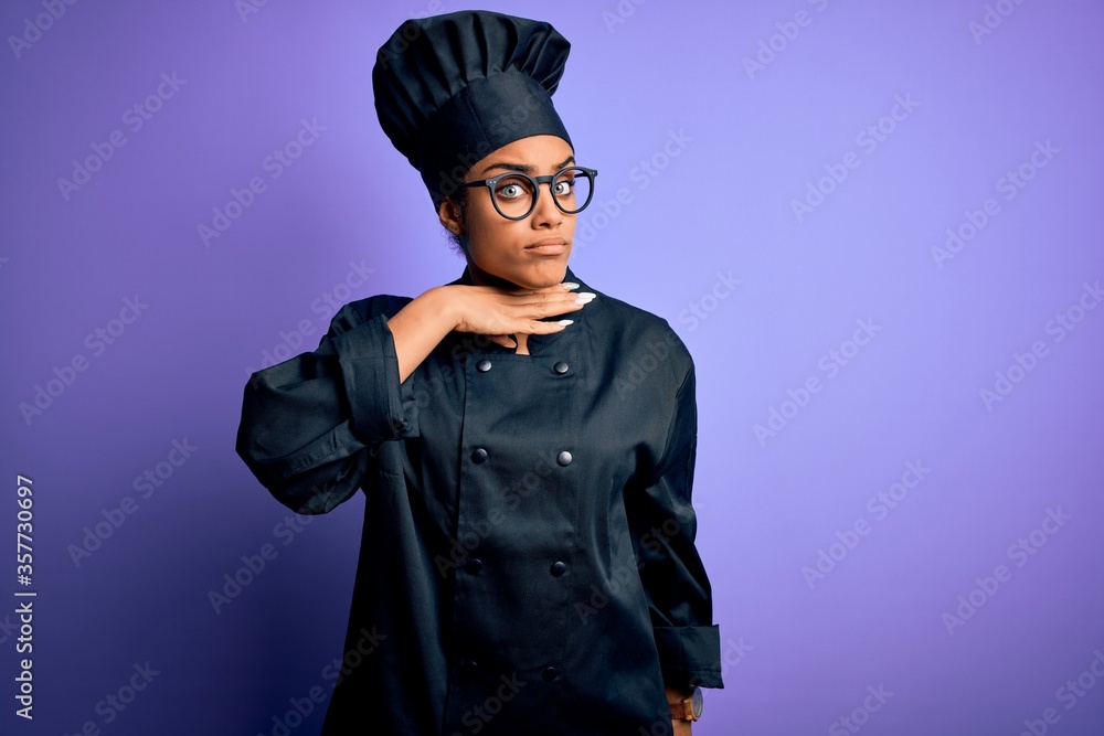 Young african american chef girl wearing cooker uniform and hat over purple background cutting throat with hand as knife, threaten aggression with furious violence Young african american chef girl wearing cooker uniform and hat over purple background cutting throat with hand as knife, threaten aggression with furious violence