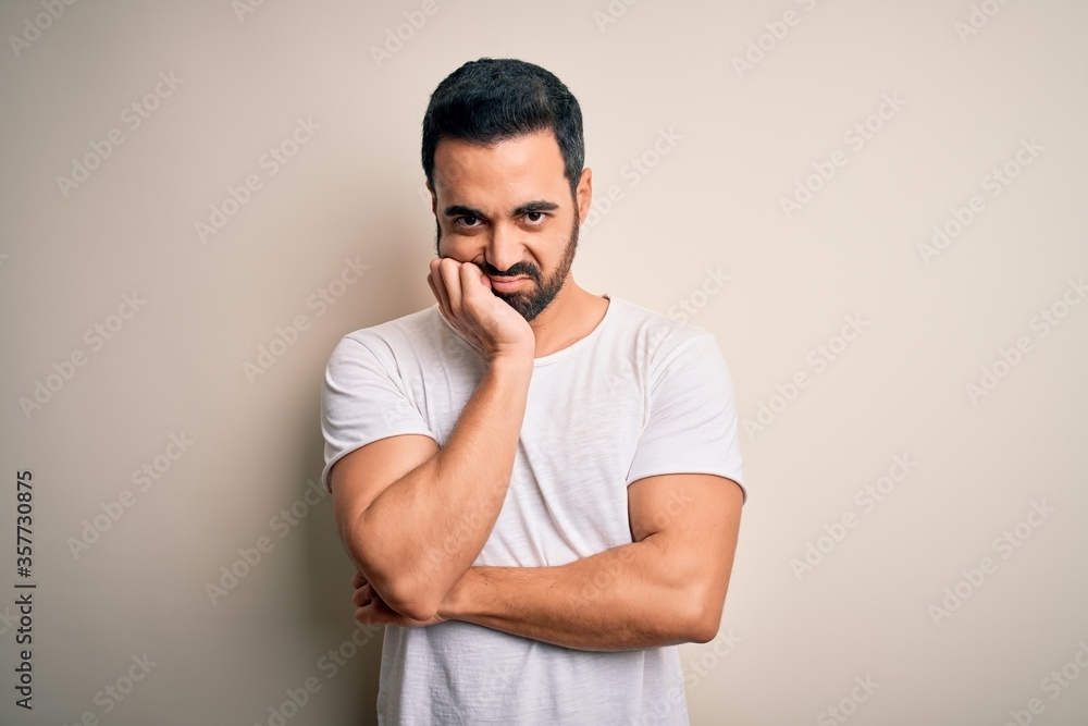Young handsome man with beard wearing casual t-shirt standing over white background thinking looking tired and bored with depression problems with crossed arms. Young handsome man with beard wearing casual t-shirt standing over white background thinking looking tired and bored with depression problems with crossed arms.