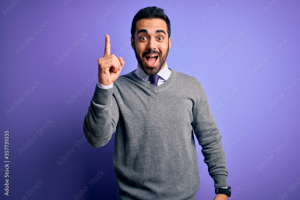 Handsome businessman with beard wearing casual tie standing over purple background pointing finger up with successful idea. Exited and happy. Number one. Handsome businessman with beard wearing casual tie standing over purple background pointing finger up with successful idea. Exited and happy. Number one.