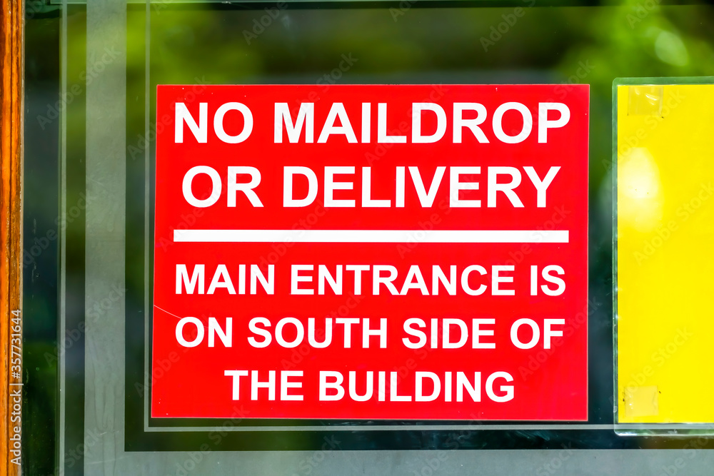 Close up of red No Maildrop Or Delivery sign on the glass wall of a building