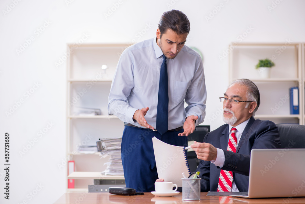 Old boss and young male employee in the office Old boss and young male employee in the office