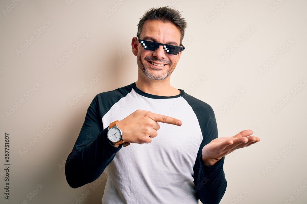 Young handsome man wearing funny thug life sunglasses meme over white  background amazed and smiling to the camera while presenting with hand and  pointing with finger. Stock Photo | Adobe Stock