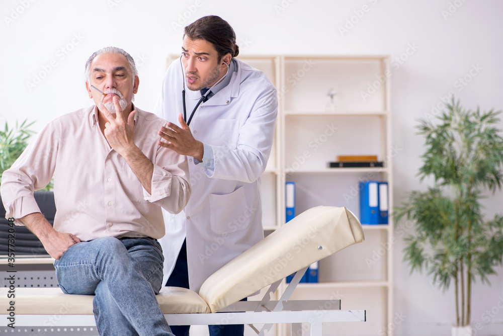 Fototapeta premium Young male doctor and old patient in antismoking concept