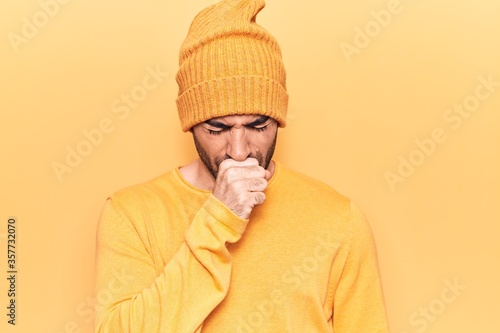 Young handsome bald man wearing sweater and wool cap feeling unwell and coughing as symptom for cold or bronchitis. health care concept.