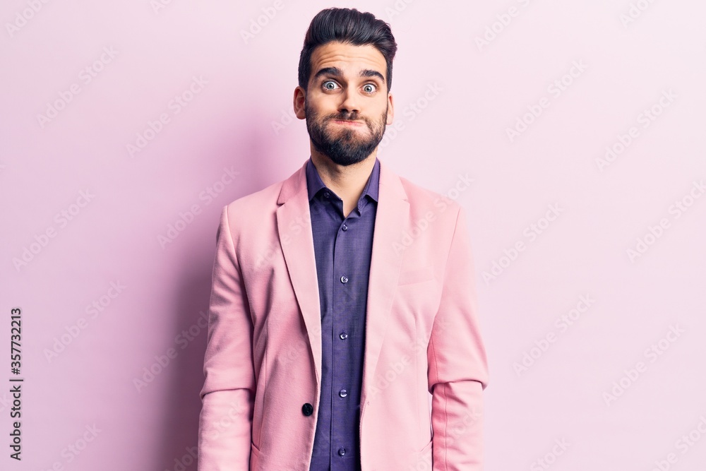 Young handsome man with beard wearing elegant jacket puffing cheeks with funny face. mouth inflated with air, crazy expression. Young handsome man with beard wearing elegant jacket puffing cheeks with funny face. mouth inflated with air, crazy expression.