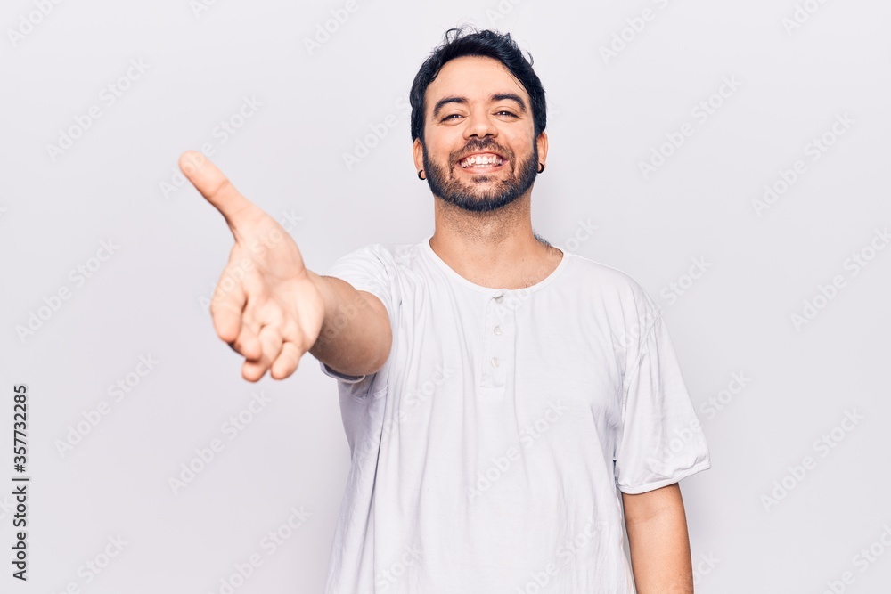 Young hispanic man wearing casual clothes smiling friendly offering handshake as greeting and welcoming. successful business. Young hispanic man wearing casual clothes smiling friendly offering handshake as greeting and welcoming. successful business.