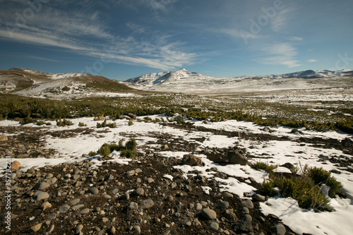 Panorama view of the rocky ground, meadow and snowy mountains.
