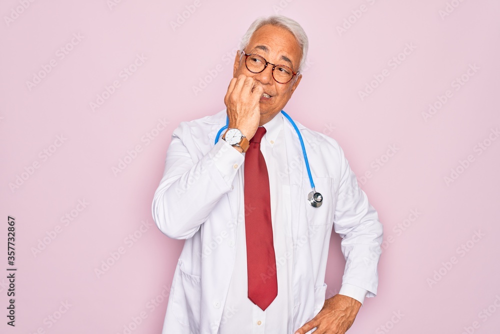 Middle age senior grey-haired doctor man wearing stethoscope and professional medical coat looking stressed and nervous with hands on mouth biting nails. Anxiety problem. Middle age senior grey-haired doctor man wearing stethoscope and professional medical coat looking stressed and nervous with hands on mouth biting nails. Anxiety problem.