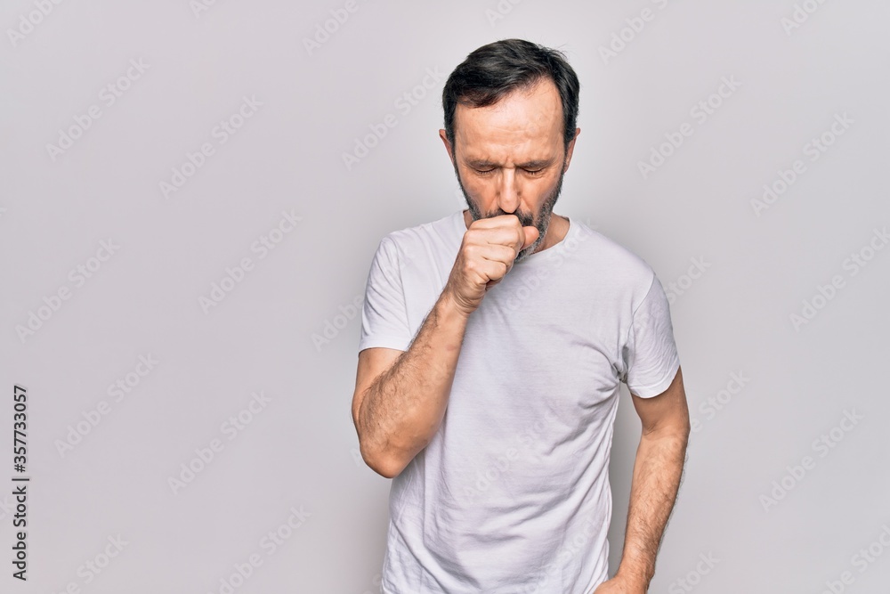 Middle age handsome man wearing casual t-shirt standing over isolated white background feeling unwell and coughing as symptom for cold or bronchitis. Health care concept. Middle age handsome man wearing casual t-shirt standing over isolated white background feeling unwell and coughing as symptom for cold or bronchitis. Health care concept.