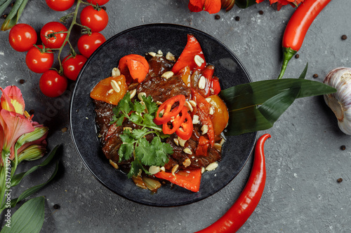 Beef wok. Traditional chinese mongolian beef stir fry in chinese cast iron wok with cooking chopsticks, stone slate background. Top view, copy space