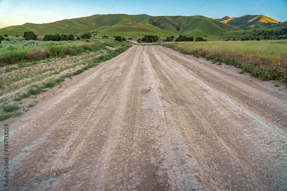 Rough road on a scenic hill landscape blanketed with lush greenery and trees Rough road on a scenic hill landscape blanketed with lush greenery and trees