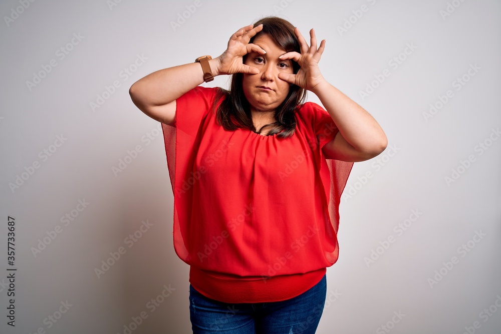Beautiful brunette plus size woman wearing casual red t-shirt over isolated white background Trying to open eyes with fingers, sleepy and tired for morning fatigue Beautiful brunette plus size woman wearing casual red t-shirt over isolated white background Trying to open eyes with fingers, sleepy and tired for morning fatigue