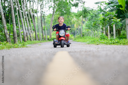 Cute little biker on road with motorcycle. Young boy on toy motorcycle. Having, funny.