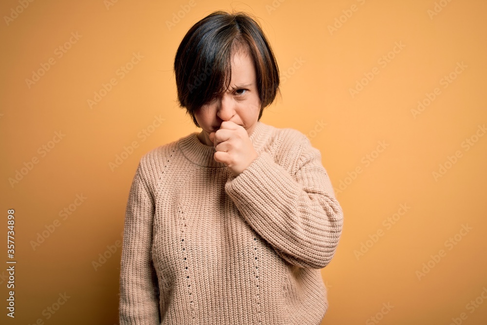 Young down syndrome woman wearing casual sweater over yellow background feeling unwell and coughing as symptom for cold or bronchitis. Health care concept. Young down syndrome woman wearing casual sweater over yellow background feeling unwell and coughing as symptom for cold or bronchitis. Health care concept.