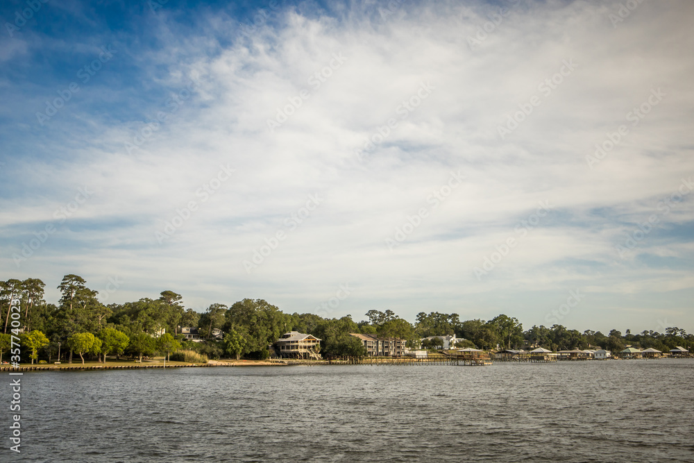 A scenic view of the coastline in Fairhope, Alabama with several houses and piers lining the waterline A scenic view of the coastline in Fairhope, Alabama with several houses and piers lining the waterline
