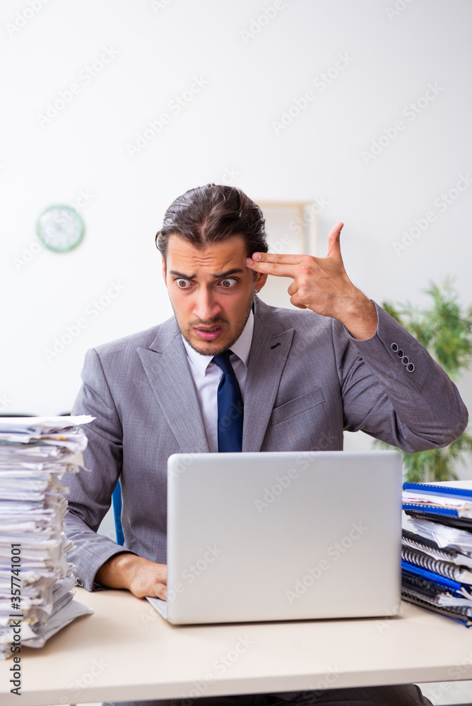 Young male employee unhappy with excessive work Young male employee unhappy with excessive work