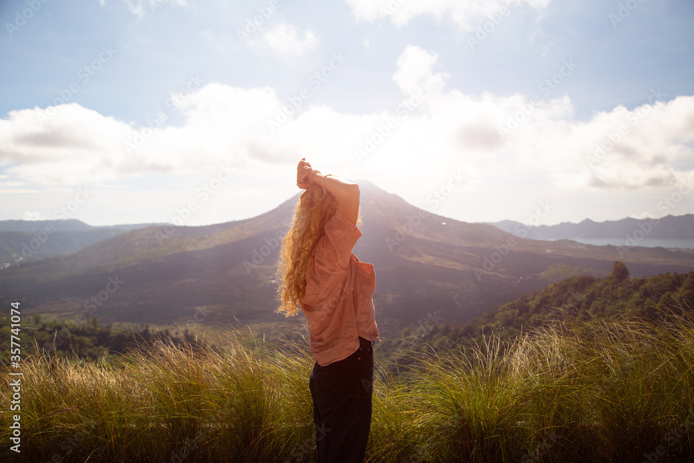 A woman looks at a mountain, a volcano. Rear view