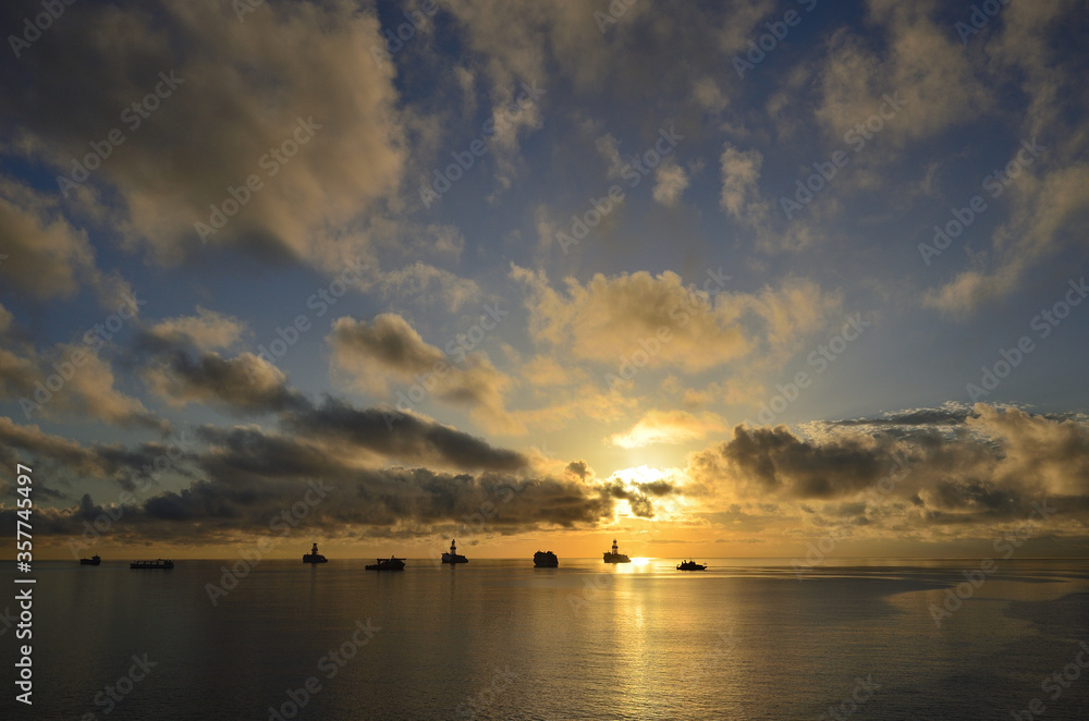 Awesome sunrise with beautiful sky of scattered clouds, calm sea and many ships in the bay