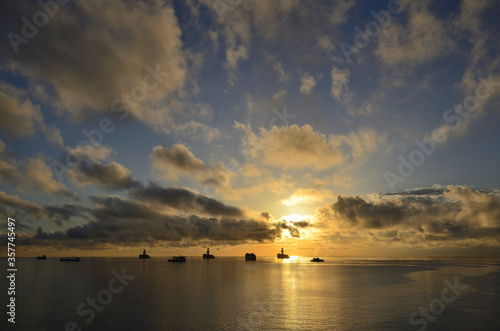 Awesome sunrise with beautiful sky of scattered clouds, calm sea and many ships in the bay © ptoscano