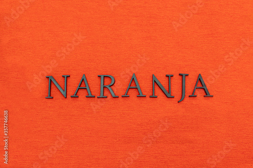 Closeup to an orange spanish word black lettering over orange texture at background. Color and fashion concept