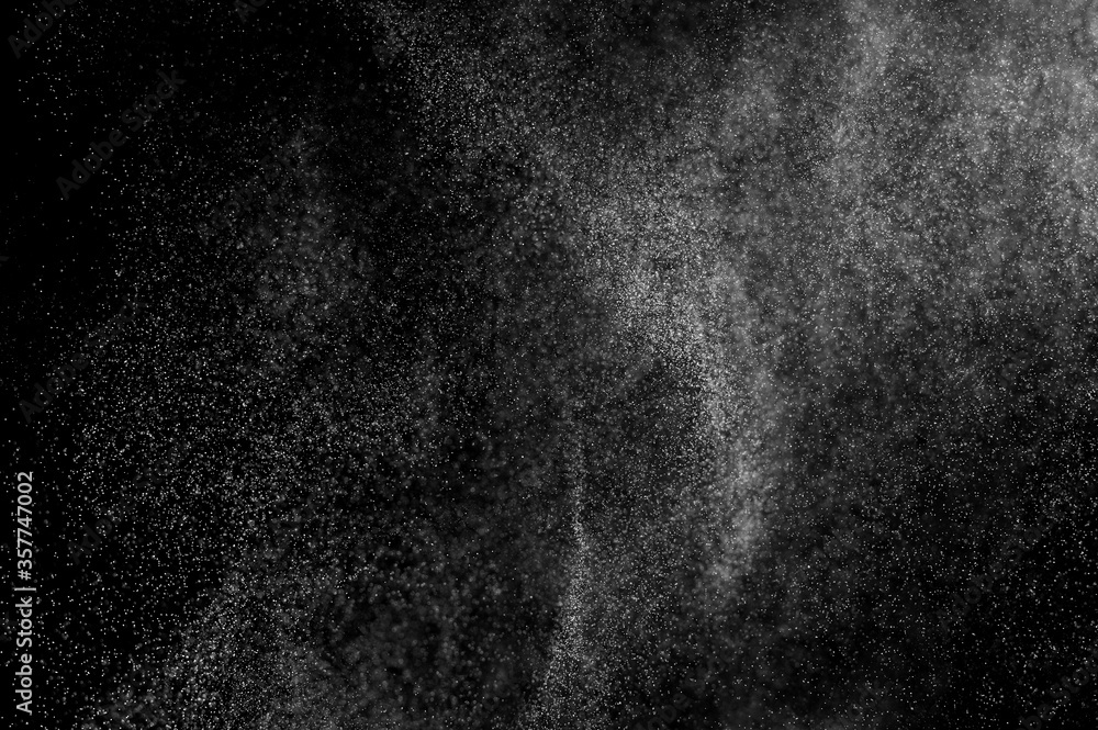 Abstract splashes of water on black background. Freeze motion of white particles. Rain, snow overlay texture.