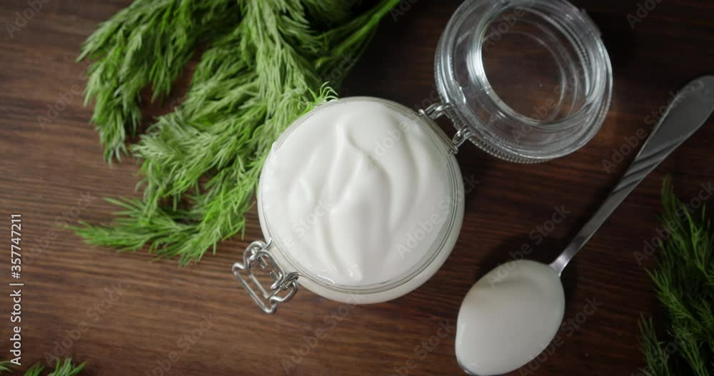 Sour cream in glass jar and spoon with dill rotates slowly. Sour cream in glass jar and spoon with dill rotates slowly.