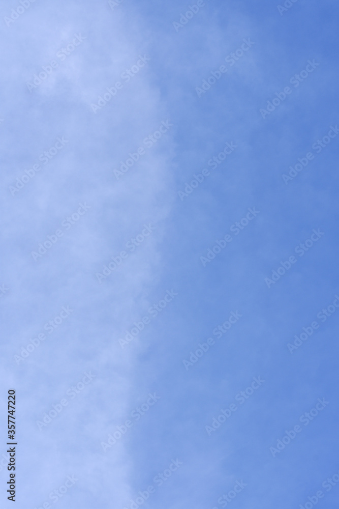 A form of soft light cloud in vertical view with blue sky background. Flow and fluctuation of natural cloudy sky environment.