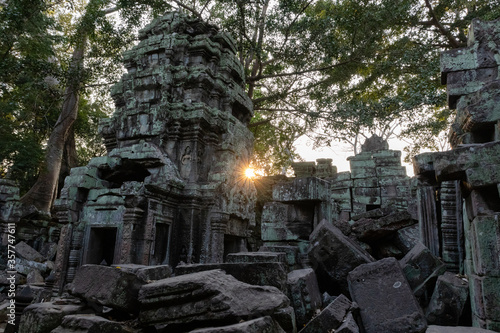 Ruins of the Ta Prohm temple at sunset surrounded by trees. Sunstar behind. One of the most visited temples in Angkor region. Bayon, Siem Reap, Cambodia, South east Asia