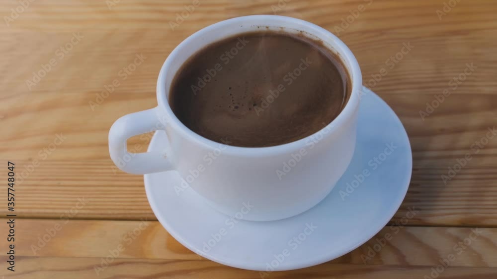 Cinemagraph of a white coffee Cup with coffee on a wooden table Cinemagraph of a white coffee Cup with coffee on a wooden table