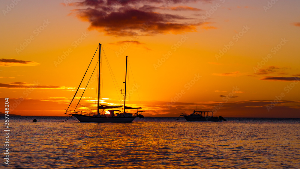 yellow and orange sunset with a sailboat silhouette
