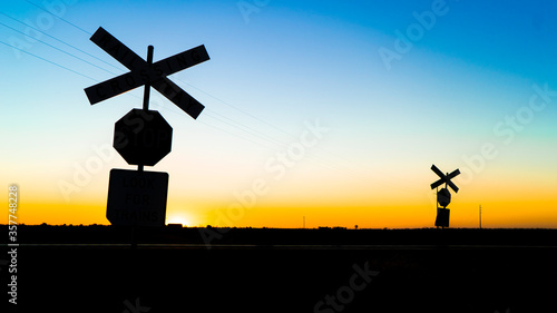 silhouette railway crossing signs at sunset