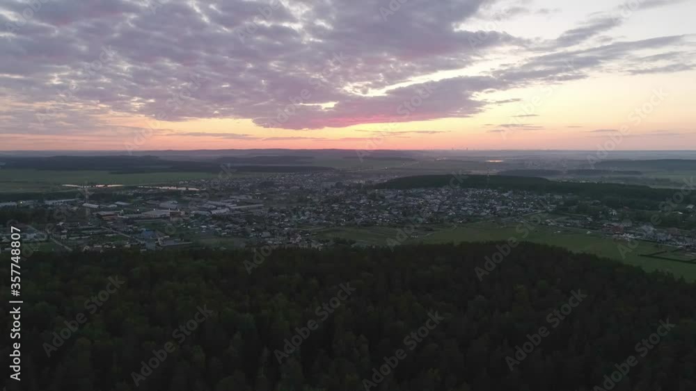 12. Aerial view of evening summer village at sunset. Camera flies from the forest. The sun has already set. There are beautiful clouds in the sky illuminated by the sun. 12. Aerial view of evening summer village at sunset. Camera flies from the forest. The sun has already set. There are beautiful clouds in the sky illuminated by the sun.