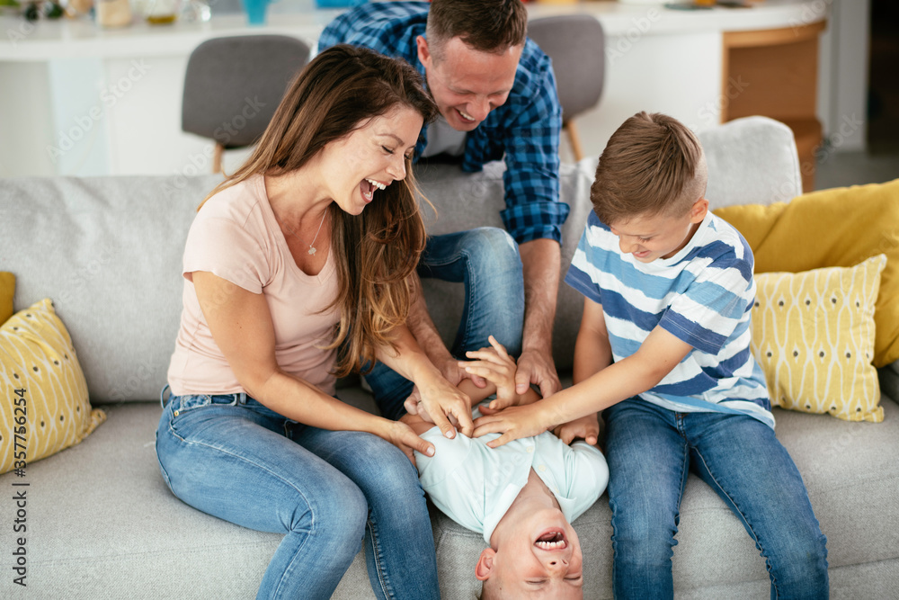  Young family enjoying at home. Happy parents with sons having fun.