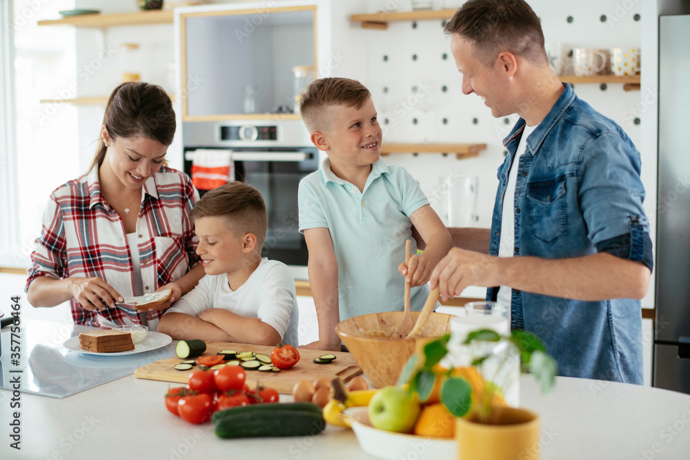 Mother and father making breakfast with sons. Young family preparing delicious food in kitchen. Mother and father making breakfast with sons. Young family preparing delicious food in kitchen.
